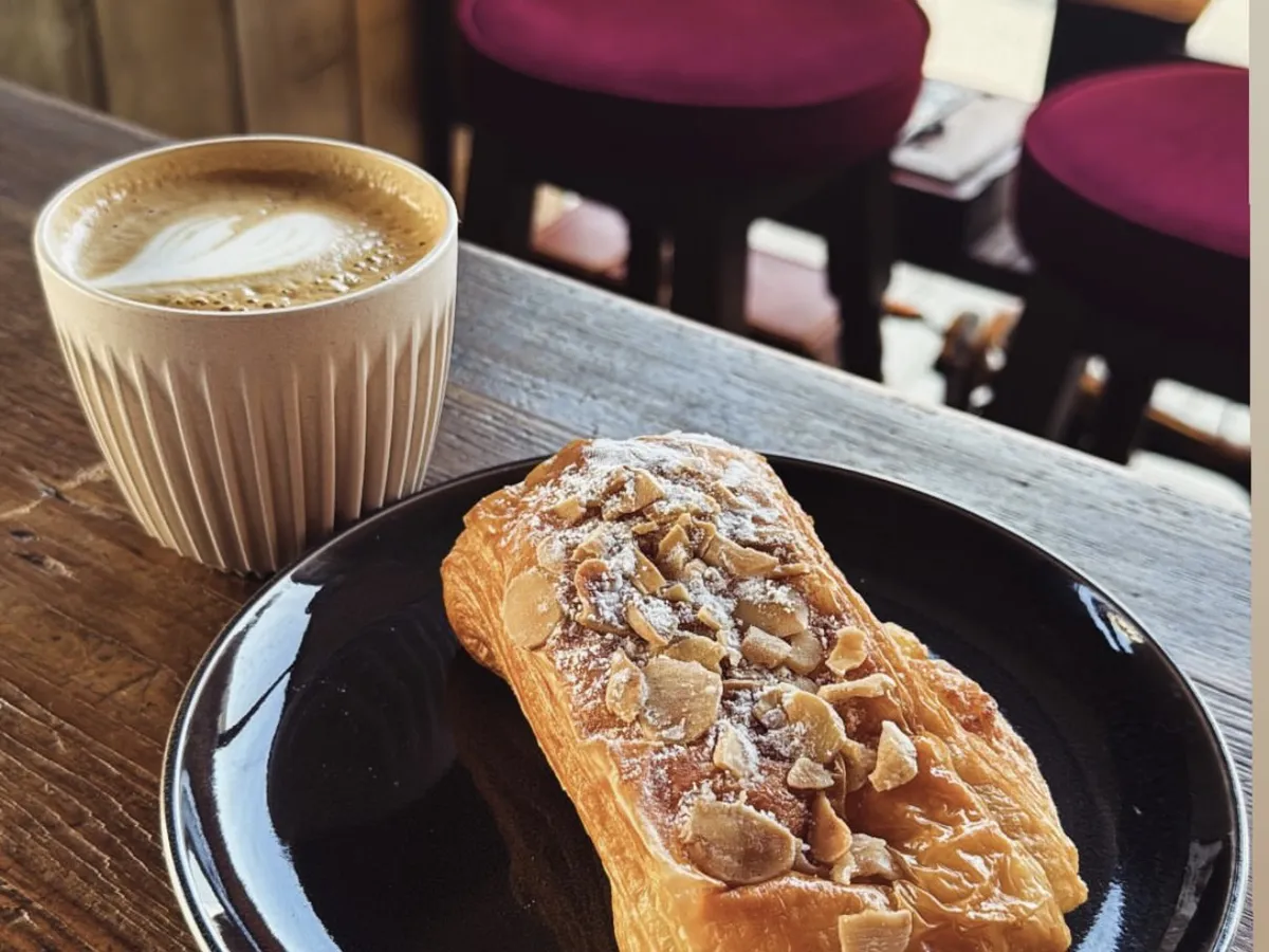 Flat white and almond pastry on a wooden table
