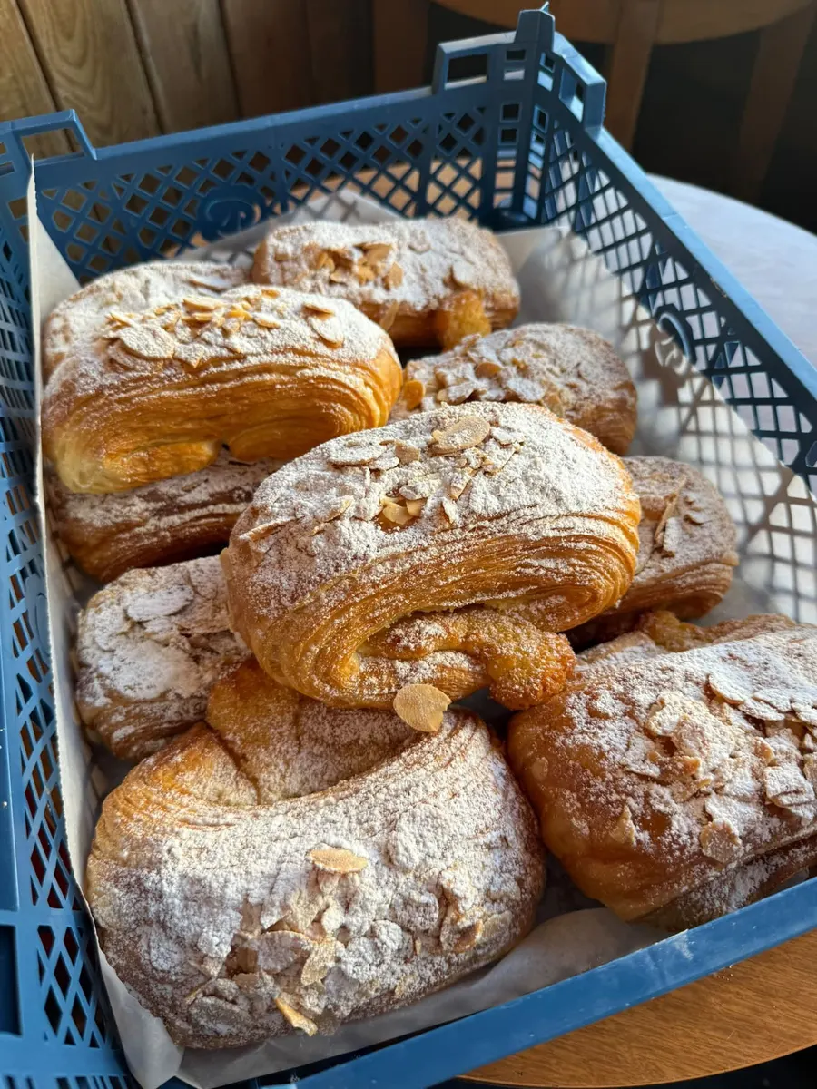 Freshly baked almond croissants in a crate from the local bakery