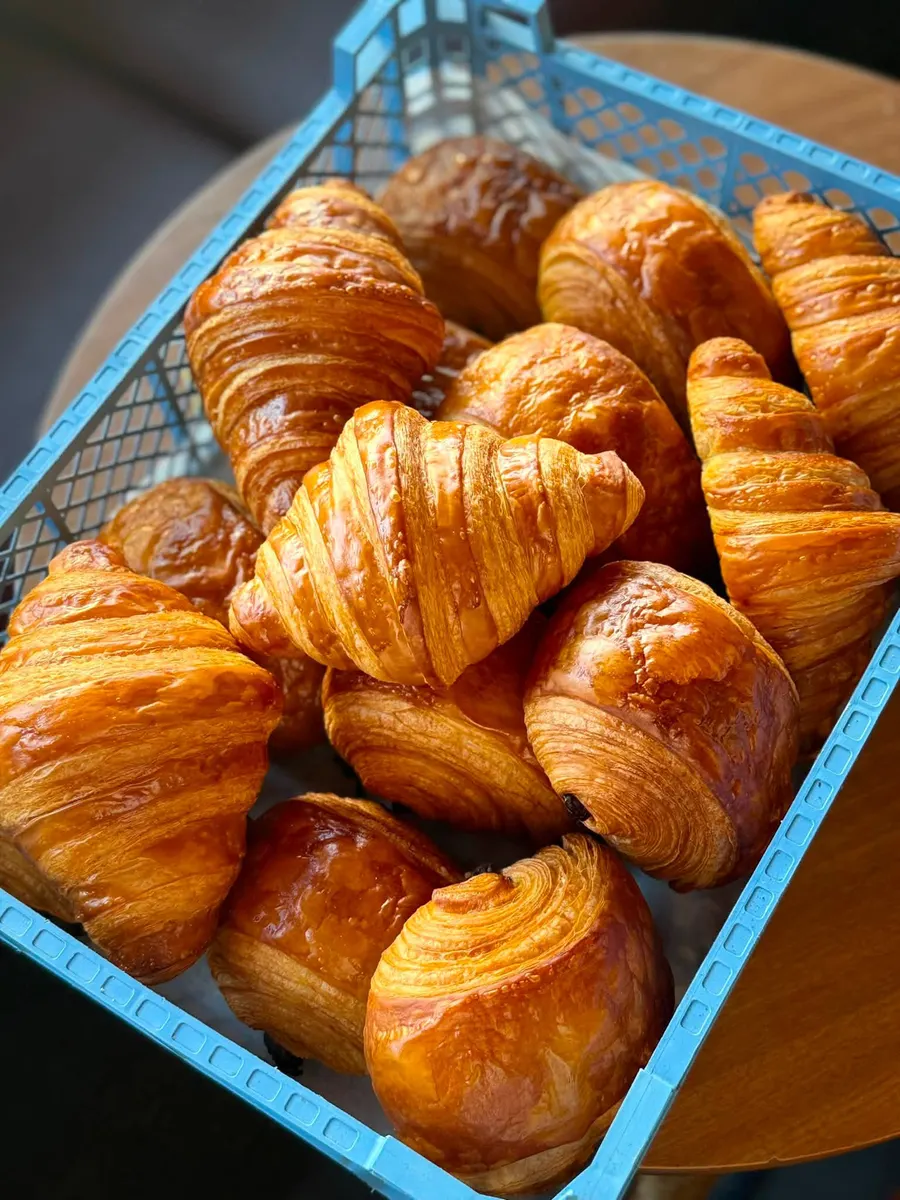A basket of glossy, freshly baked croissants
