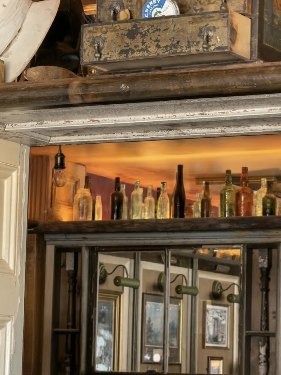 Antique bottles and lamps mirrored in the back bar