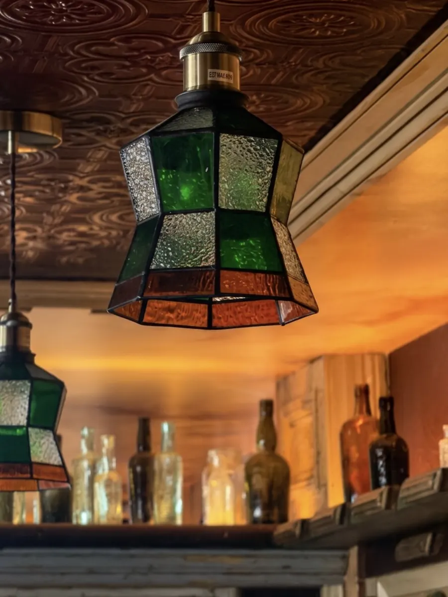 Green stained-glass pendant lamps beneath the pressed-tin ceiling