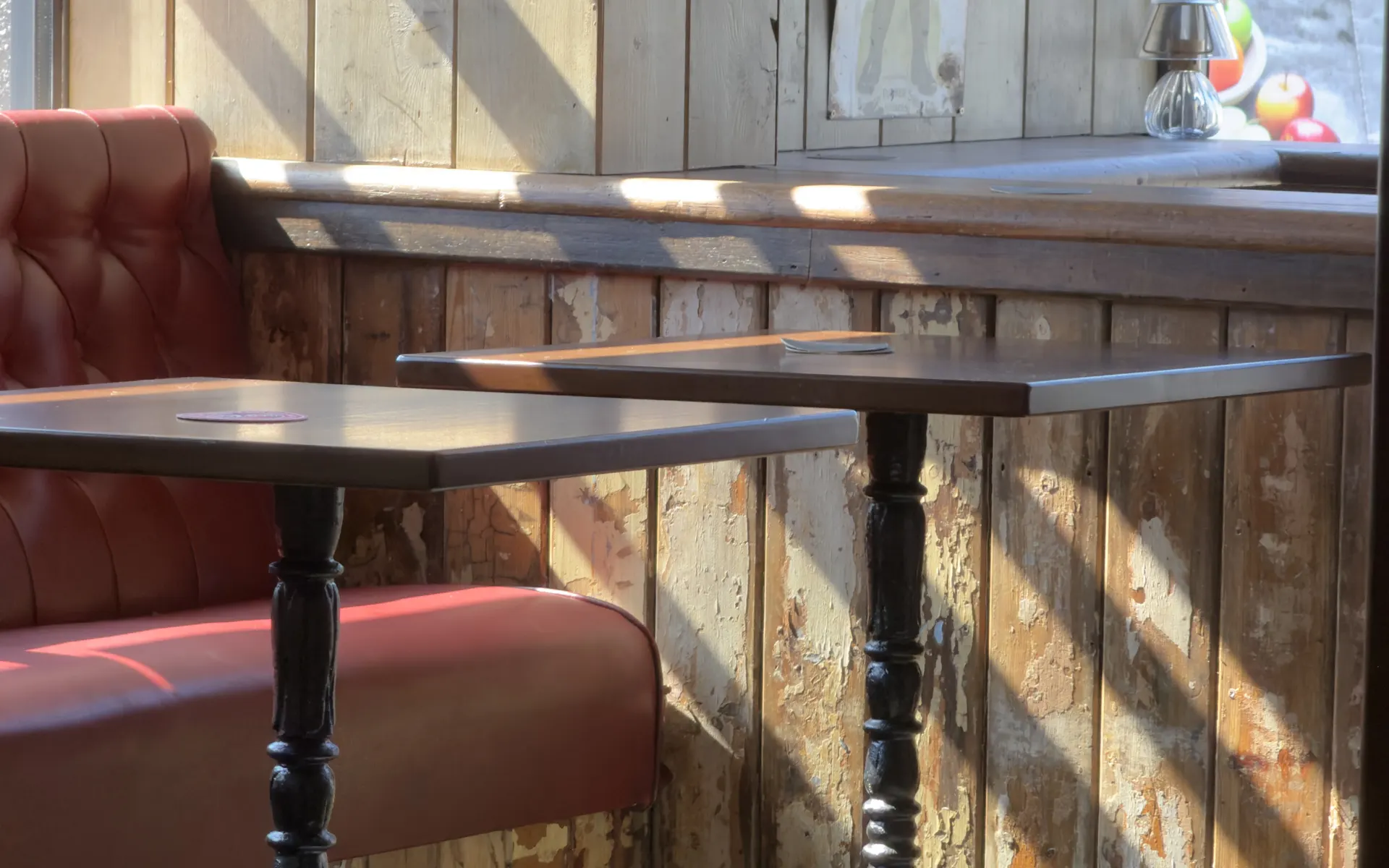 Morning sun across the tables and red leather banquette inside Leicester House